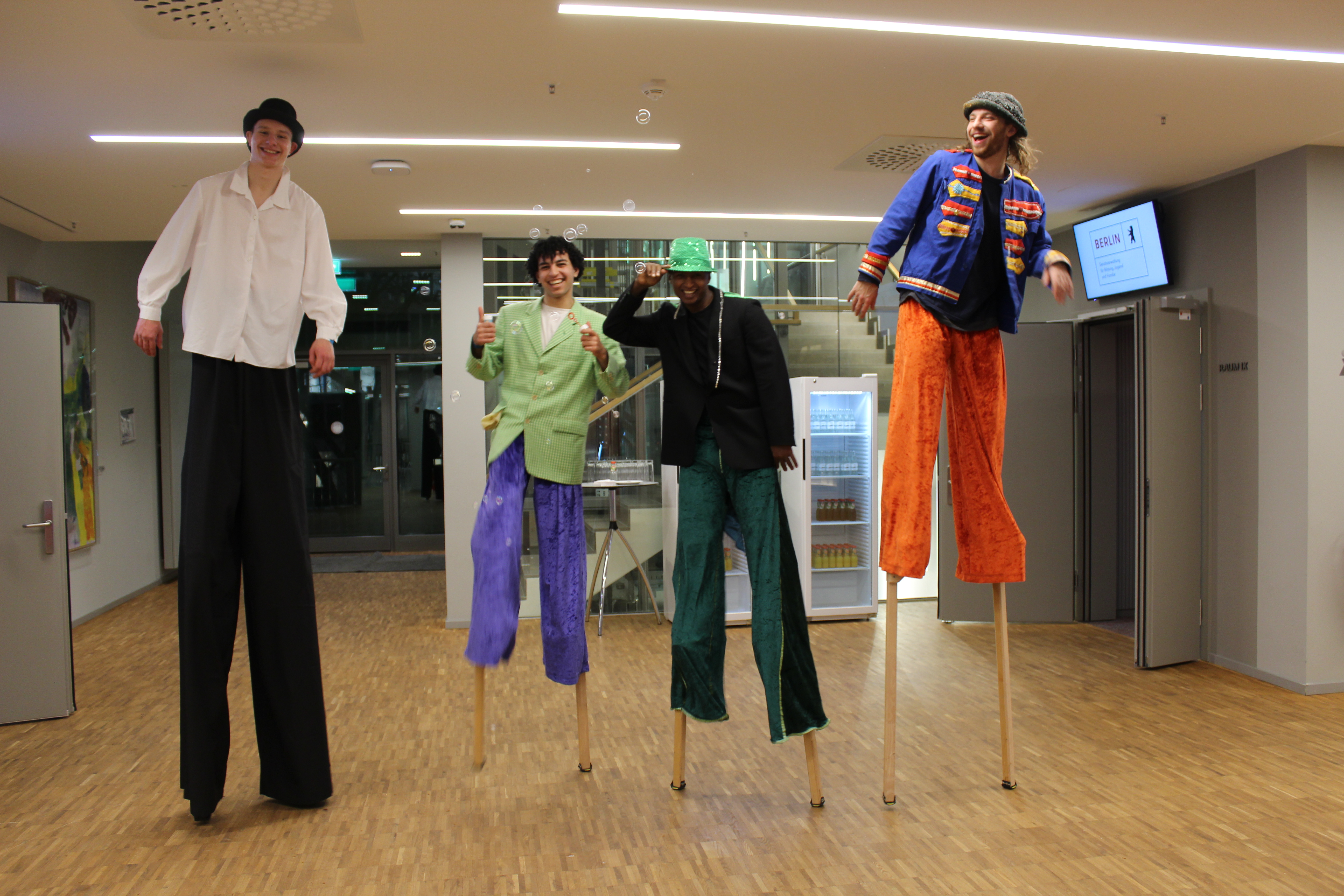 4 Personen in bunten Kostümen auf Stelzen